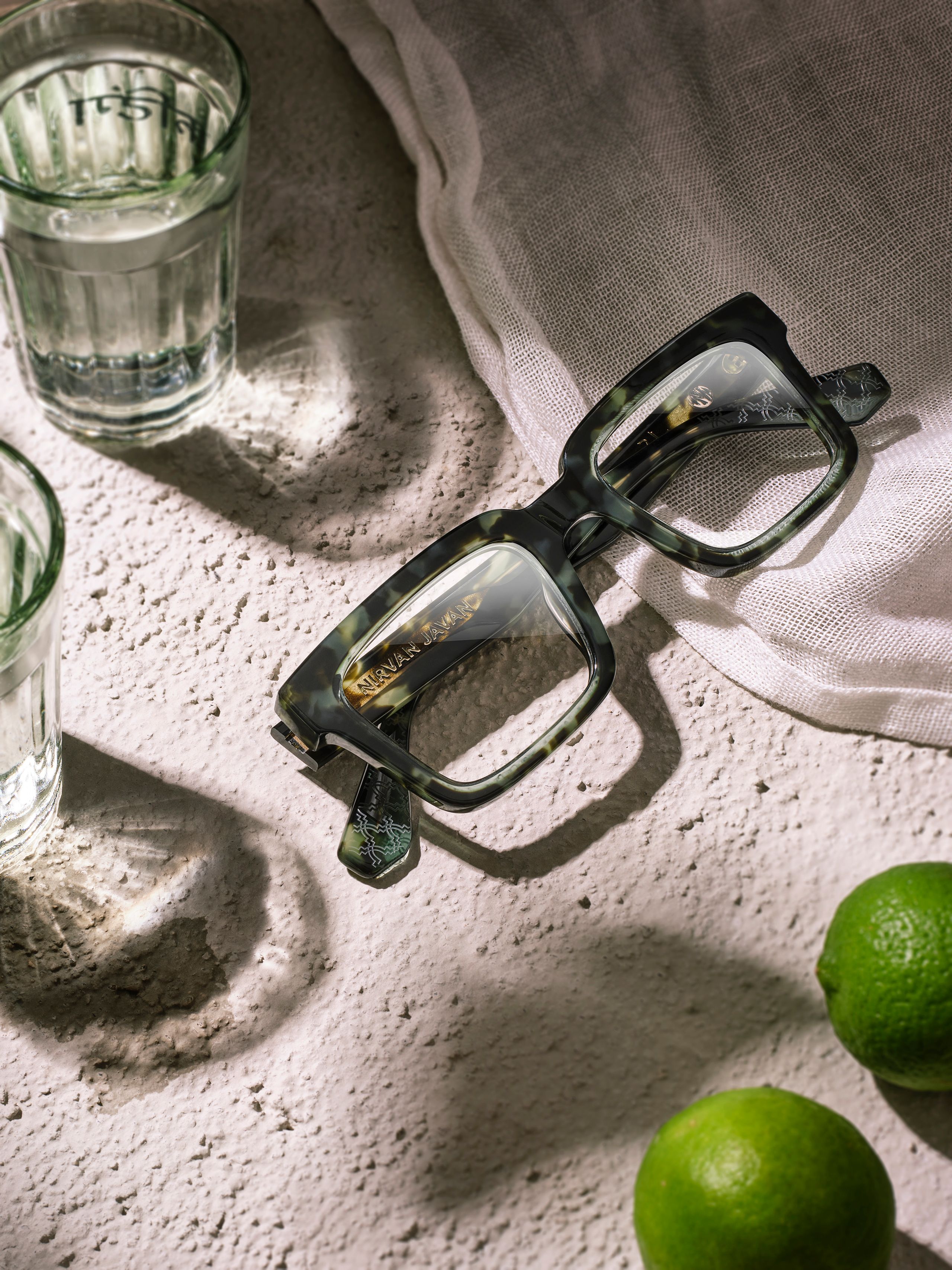 Grüne Brille mit Stoff, Wassergläsern und Limetten