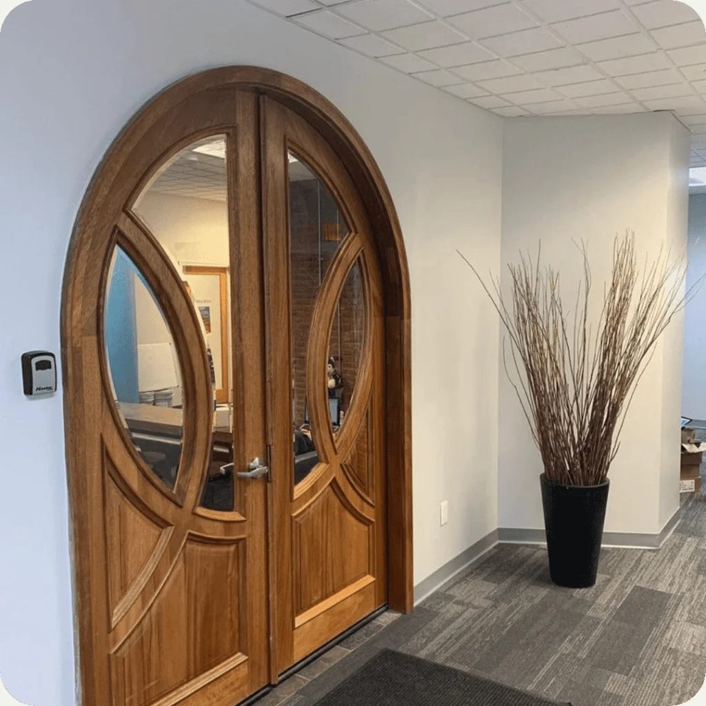 Arched wood and glass entrance framed by white painted walls
