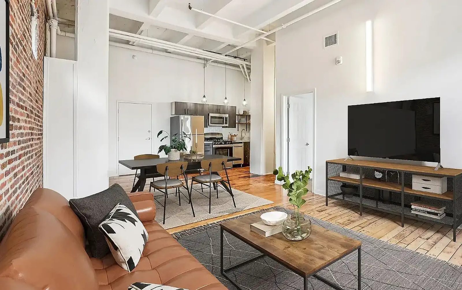 White painted walls and ceiling beams in a furnished loft with exposed brick and wood flooring