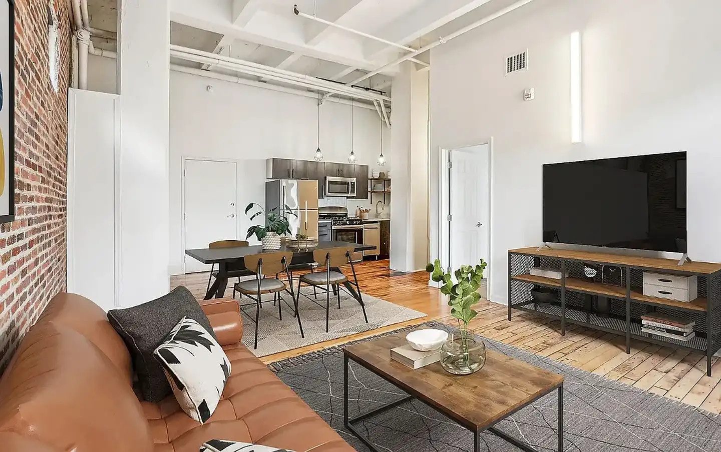 White painted walls and ceiling beams in a furnished loft with exposed brick and wood flooring