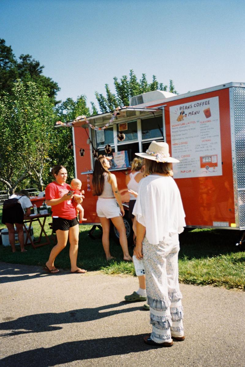 A crowd of people standing in front of the Beans Coffee trailer