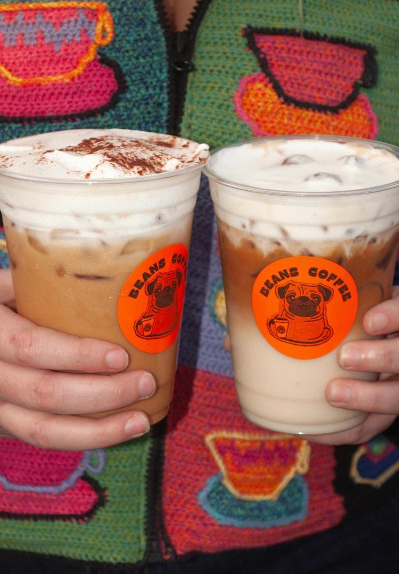 Two Beans coffee latte with Beans coffee pug stickers in front of a sweater
