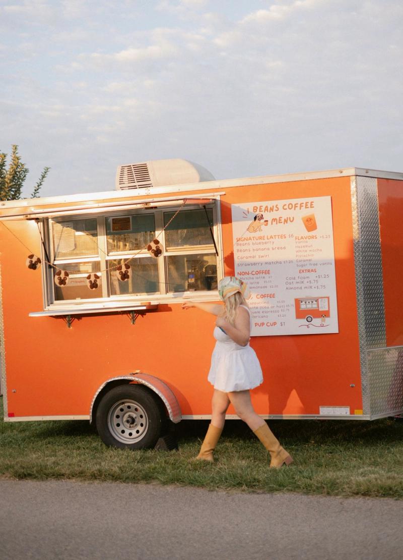 Orange Beans Coffee trailer with a woman standing in front of it