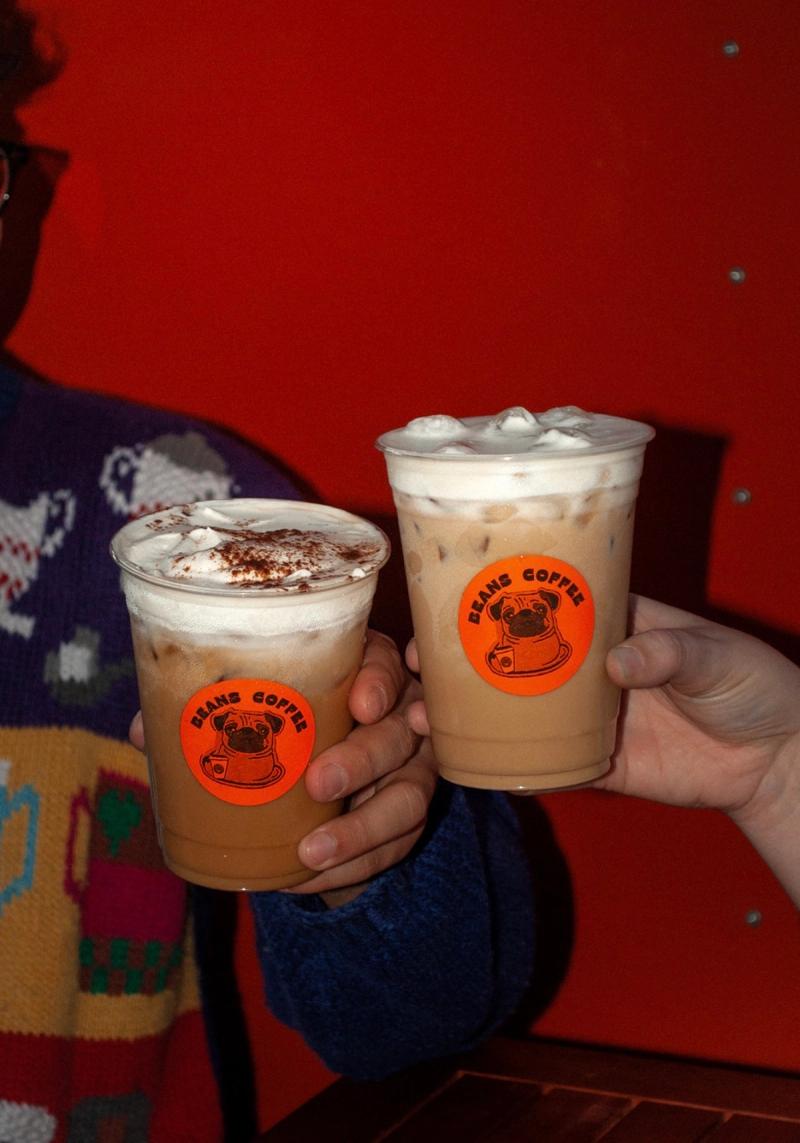 Two iced lattes touched together, pug stickers facing out, in front of the red cart