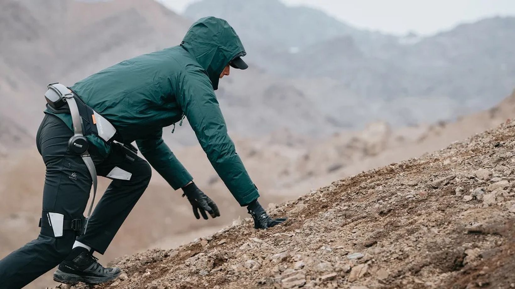 Hiker wearing a Hypershell powered exoskeleton on rocky mountain terrain