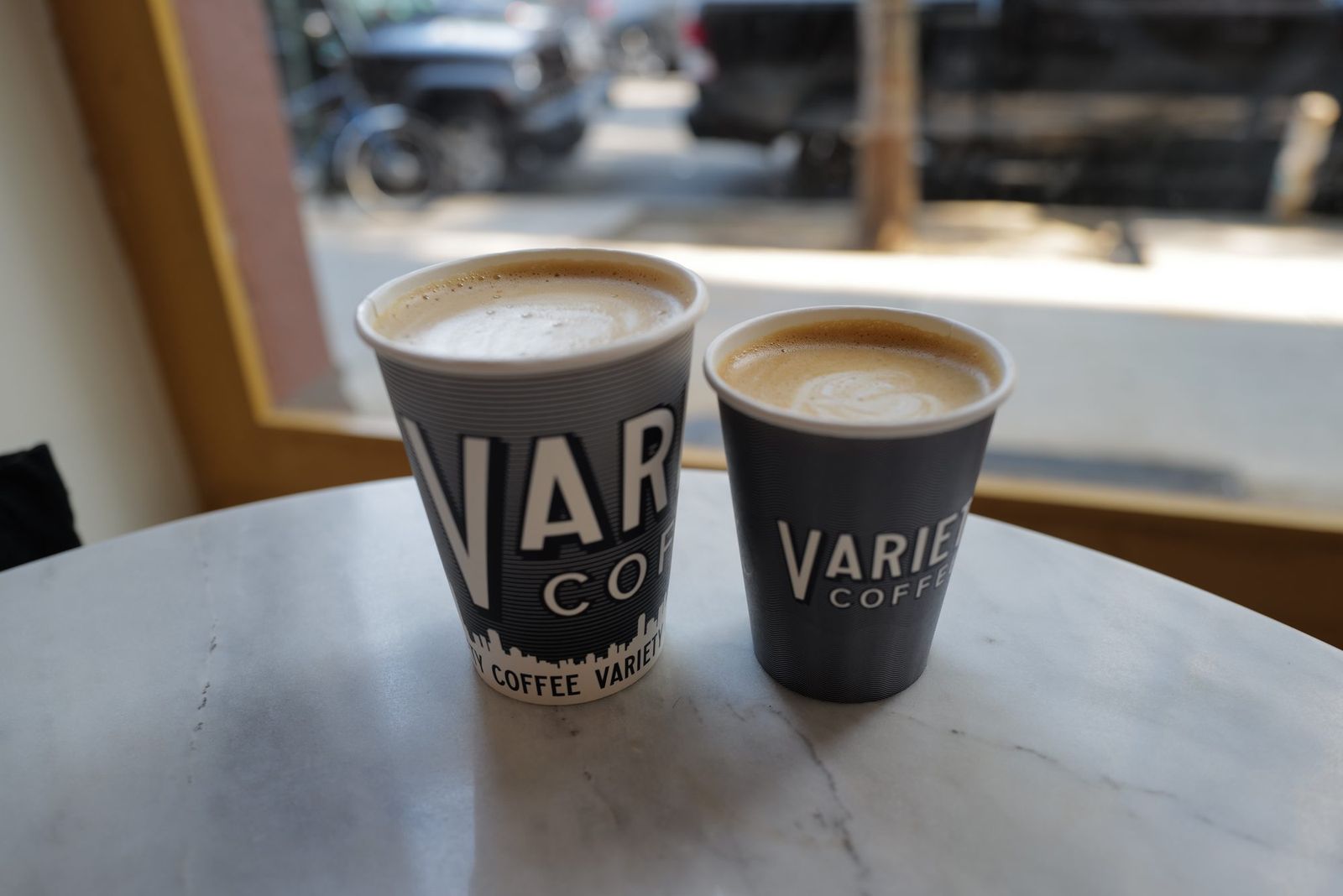 ‘VARIETY’ 로고가 찍힌 컵 두 잔. 대리석 테이블 위에서 창밖 볕을 받는다.
