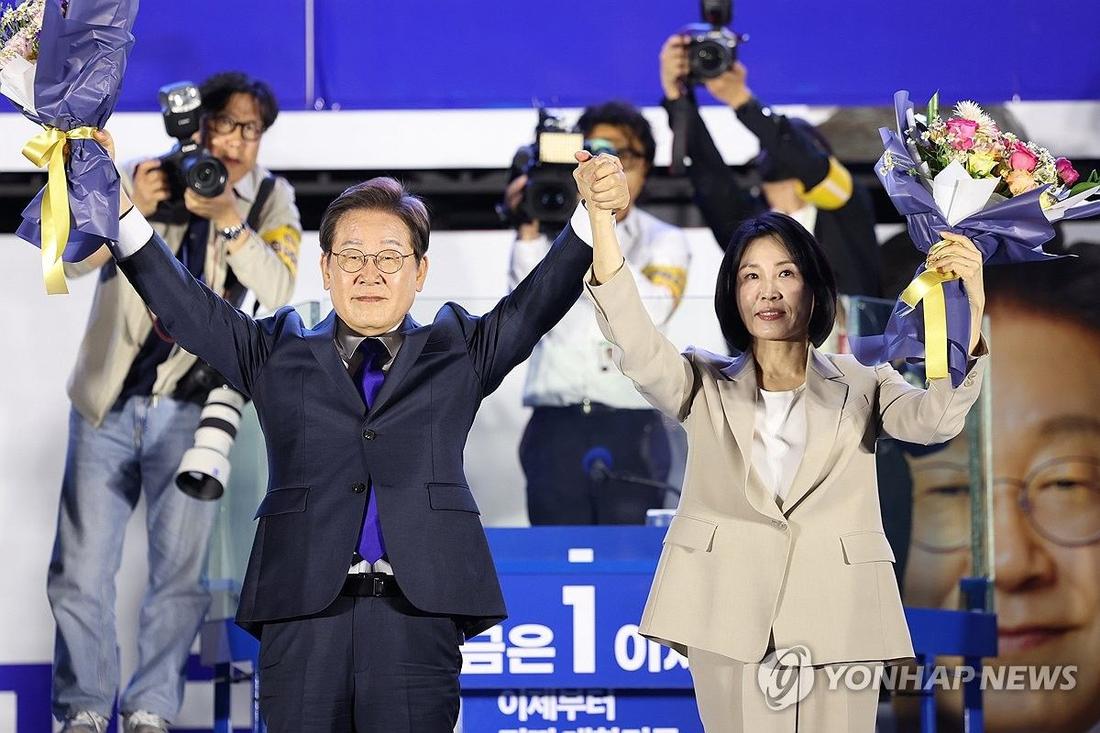 시민들 향해 두 팔 들어올리는 이재명 후보 내외 (서울=연합뉴스) 김주성 기자 = 제21대 대통령 당선이 확실시되는 더불어민주당 이재명 대선 후보와 부인 김혜경 여사가 4일 서울 여의도 국회 인근에서 당 주최로 열린 국민개표방송 행사에 참석해 꽃다발을 받고서 시민들을 향해 두 팔을 들어올려 인사하고 있다. 2025.6.4 [공동취재] utzza@yna.co.kr