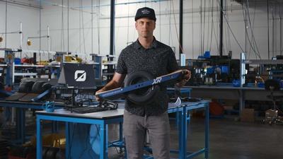 Kyle Doerksen stands in the Onewheel factory holding a Onewheel