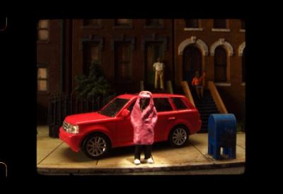 A miniature interpretation of a rapper leaning against his car