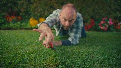 person cuts grass with scissors