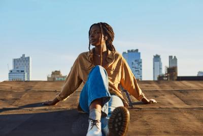 Person wearing Beats headphones and sitting on a rooftop at sunset