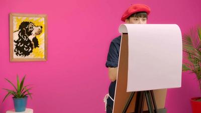 A woman in a beret paints in front of a pink wall