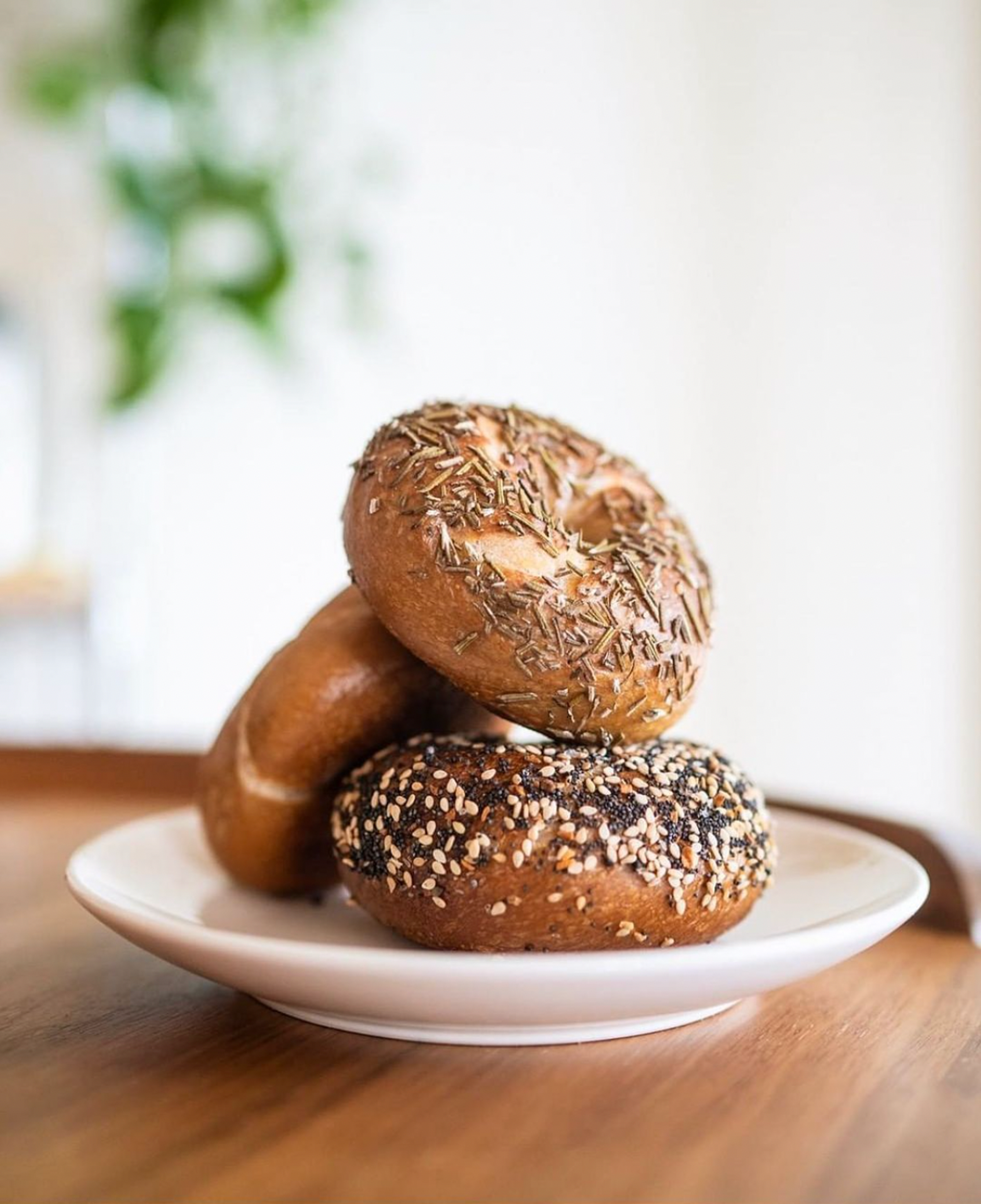 white plate with three bagels on it sitting on a wood table