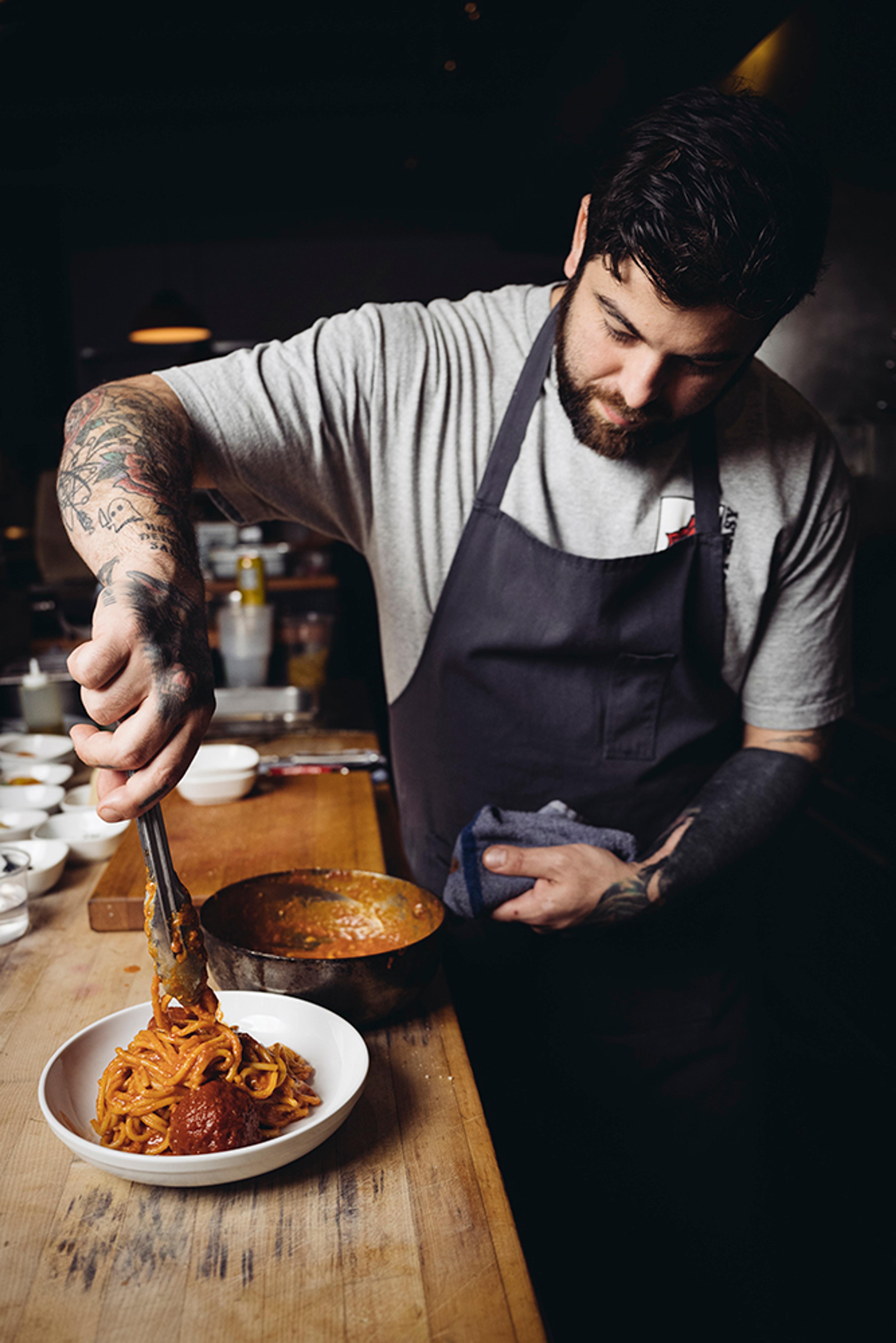 Chef twirling spaghetti with meatballs in bowl 