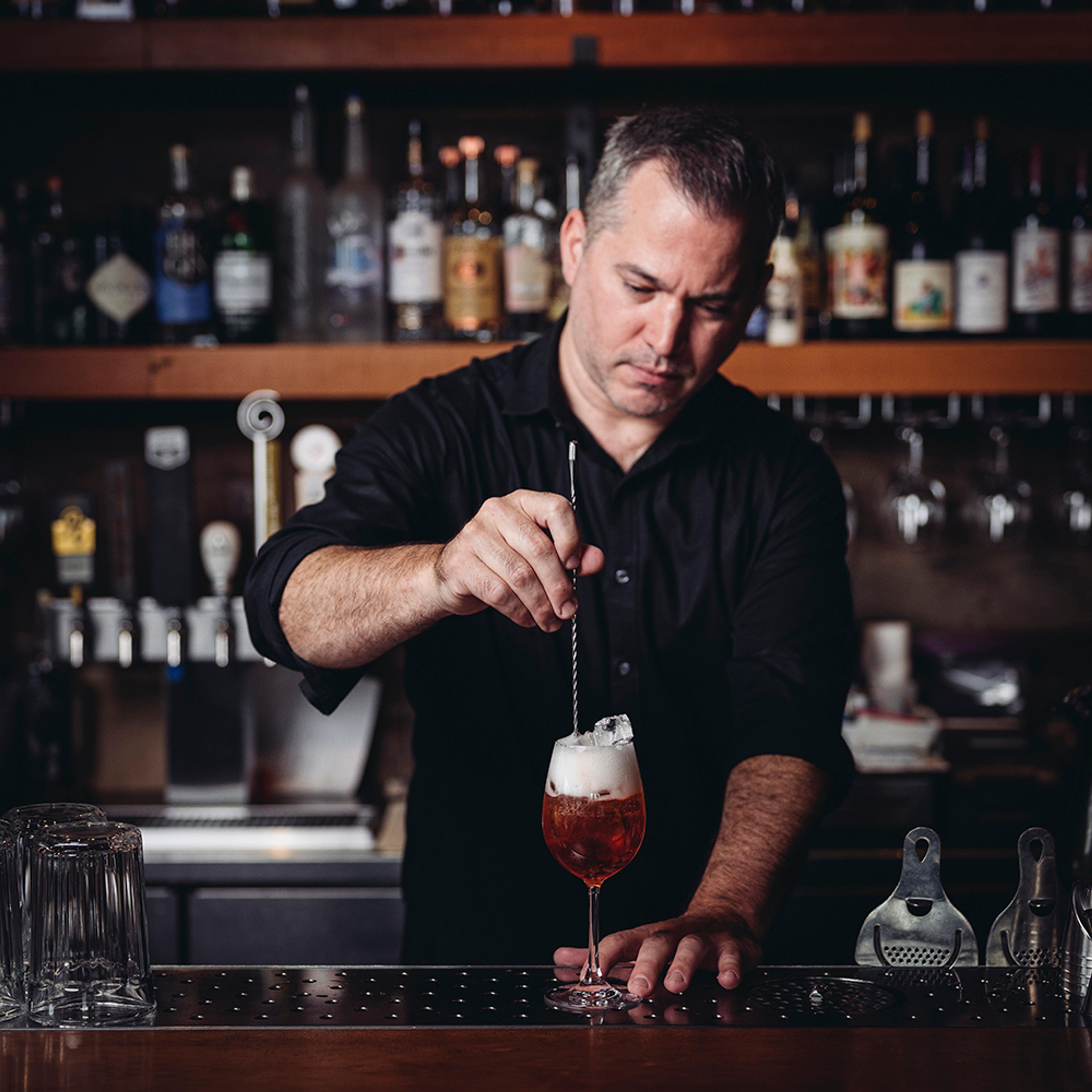 Bartender stirring spritz cocktail in wine glass