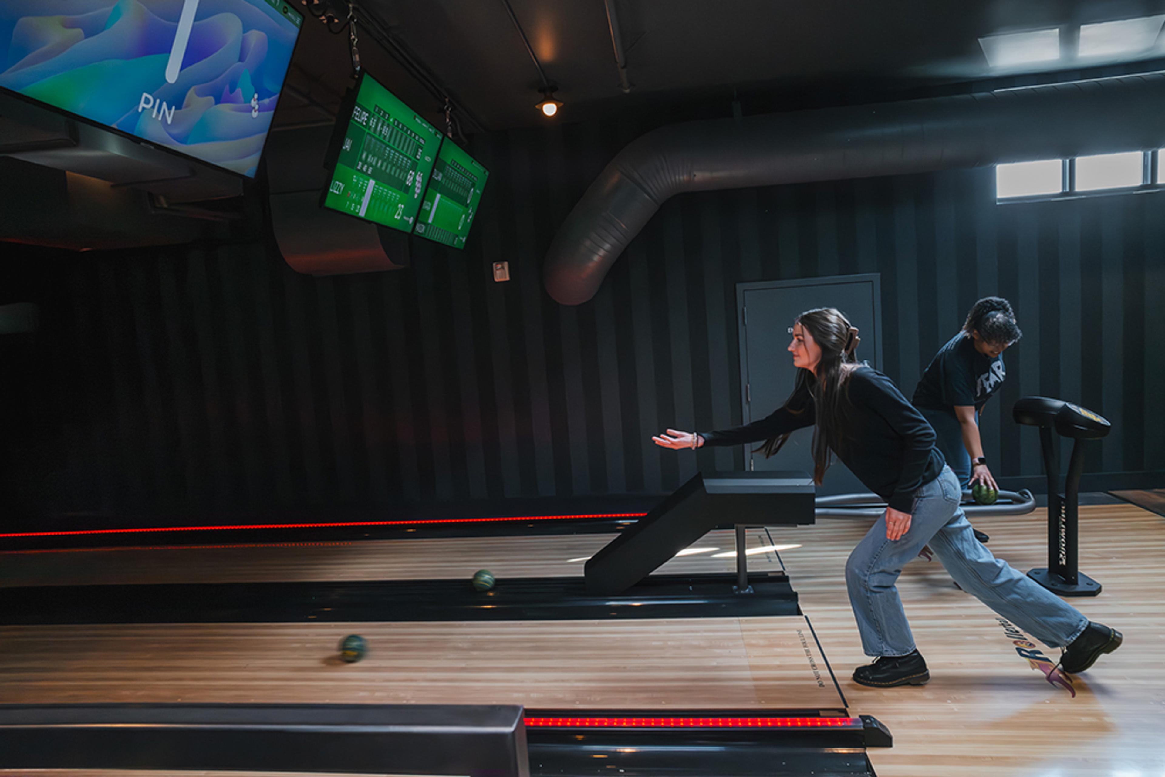 Young woman rolling a ball on bowling lane