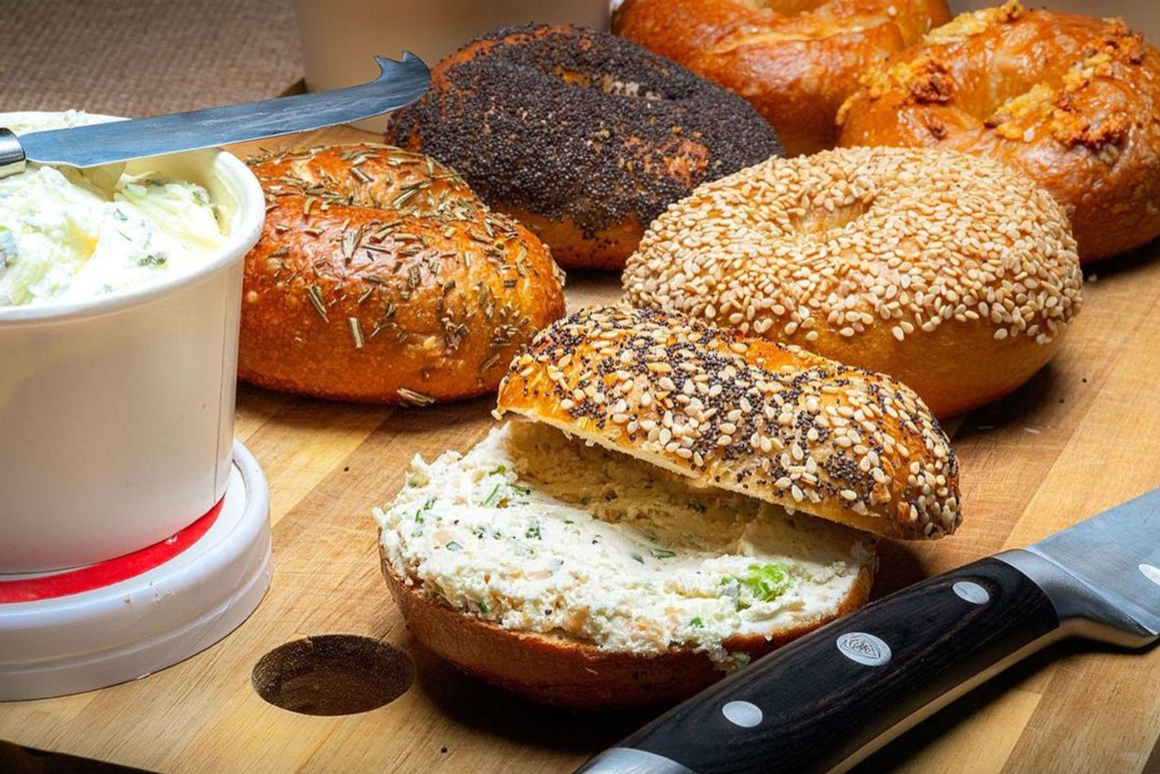 bagels with schmear on a cutting board with a knife
