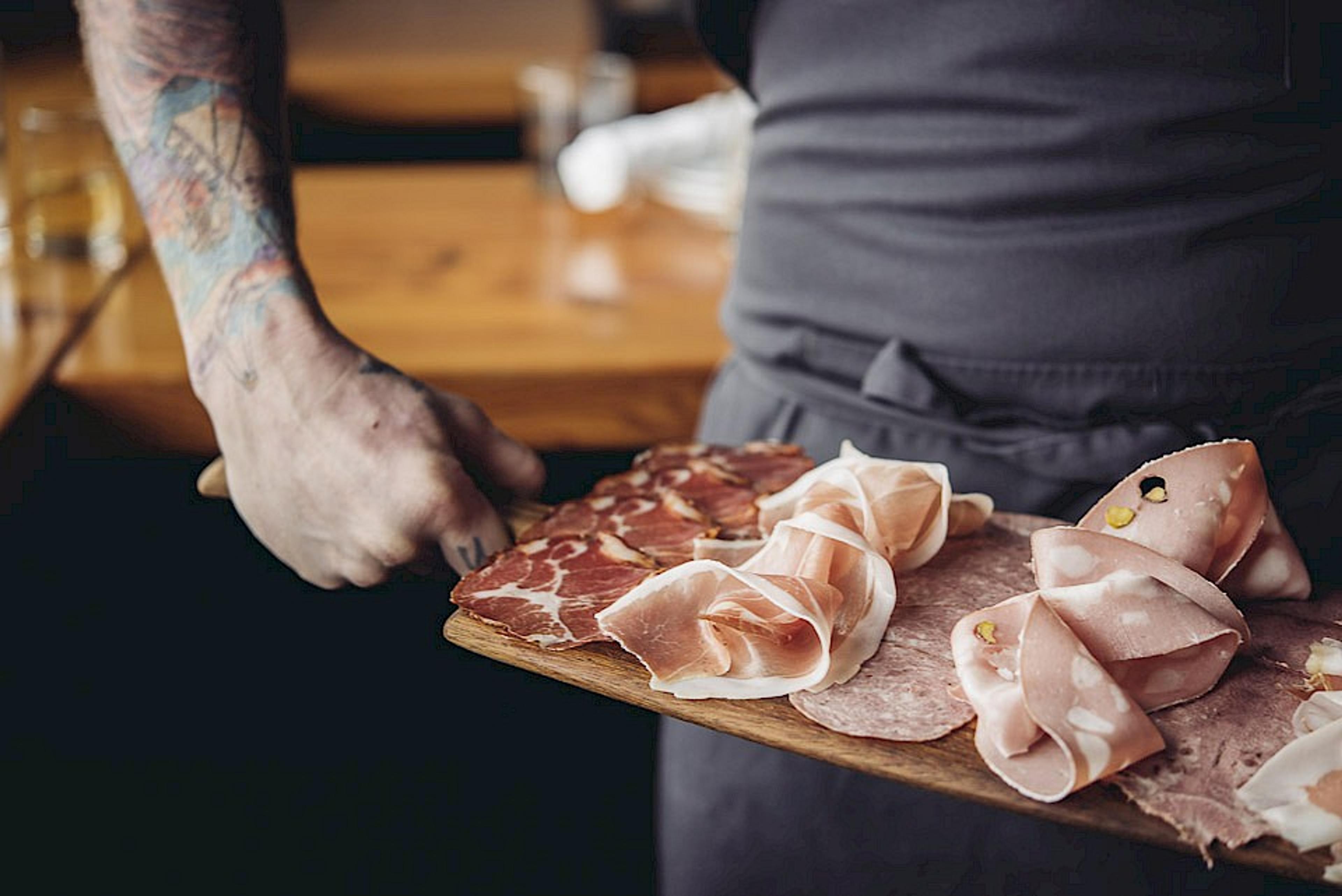 chef holding assorted cured meats on board