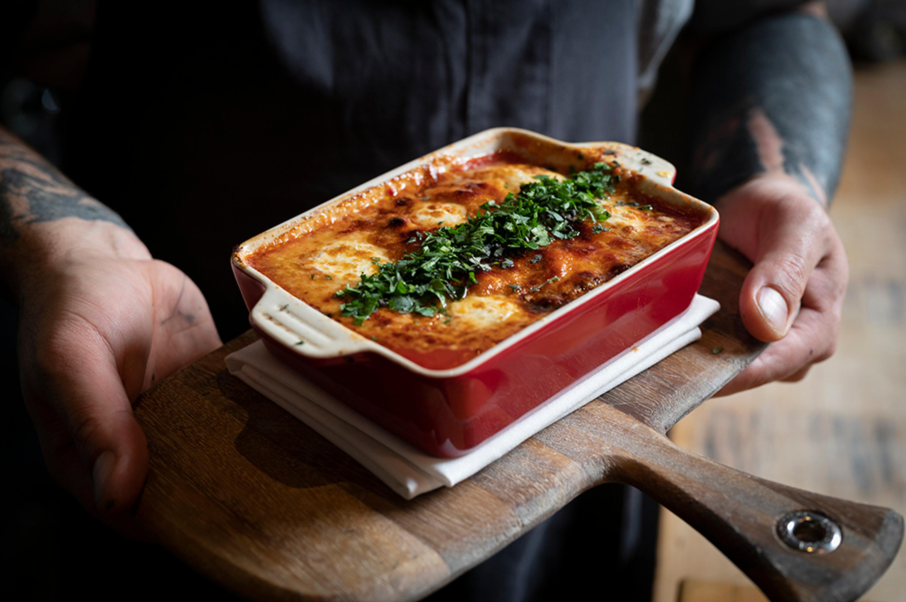 Chef carrying baked semolina gnocchi on board