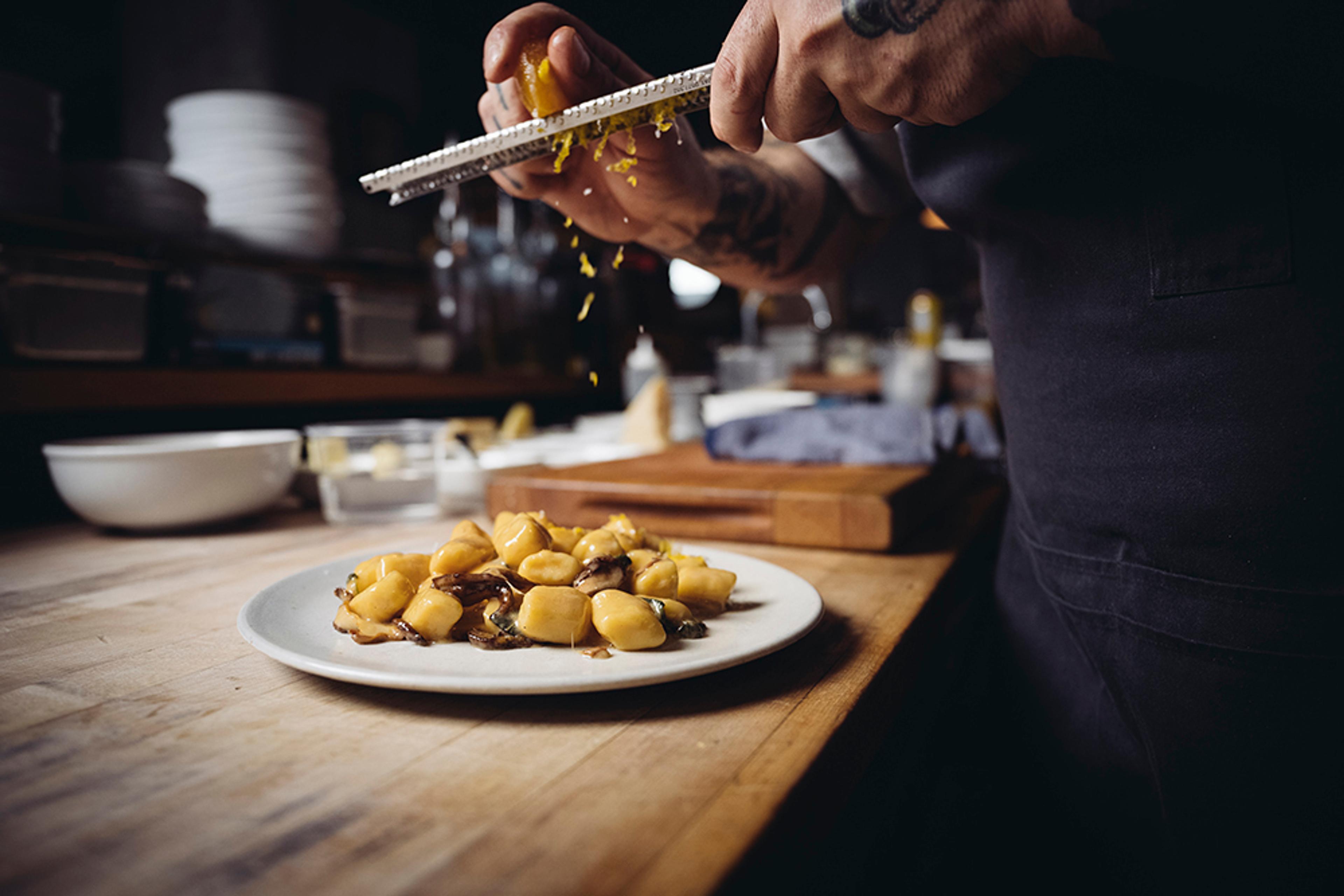 chef shaving lemon zest of potato gnocchi