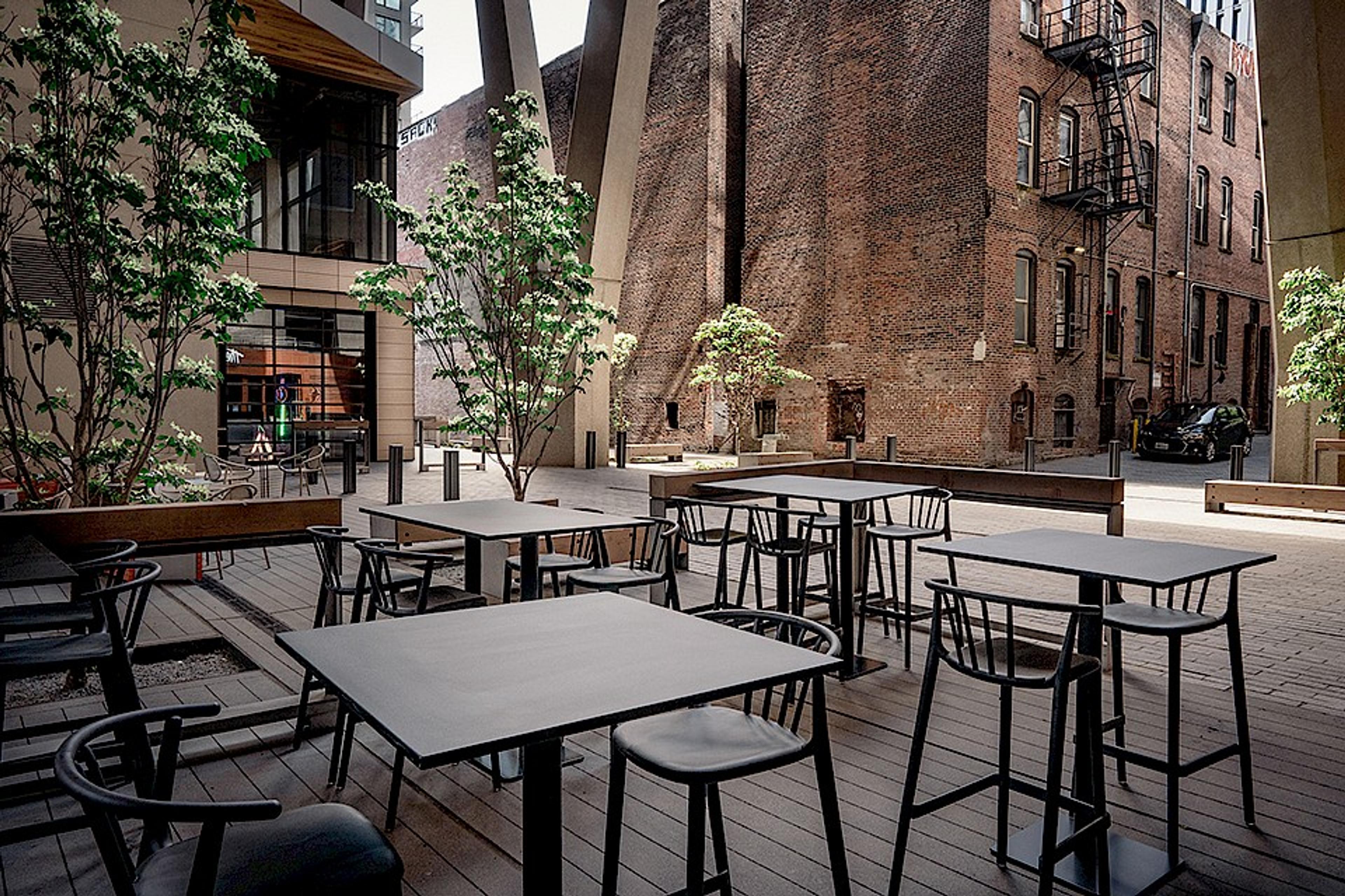 patio tables looking out onto piazza style courtyard with old brick building and trees