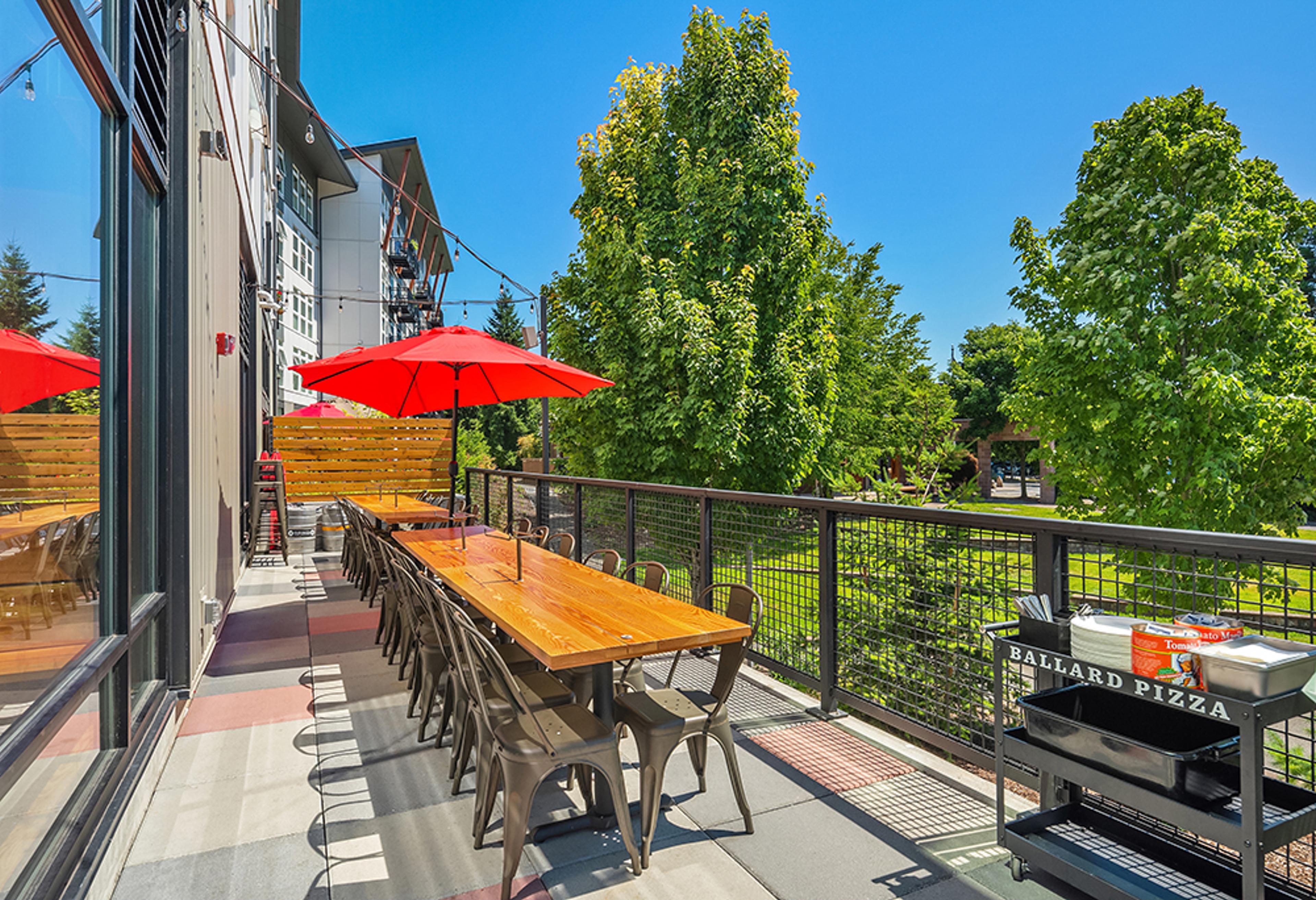 long patio table with tree views and red umbrella for shade