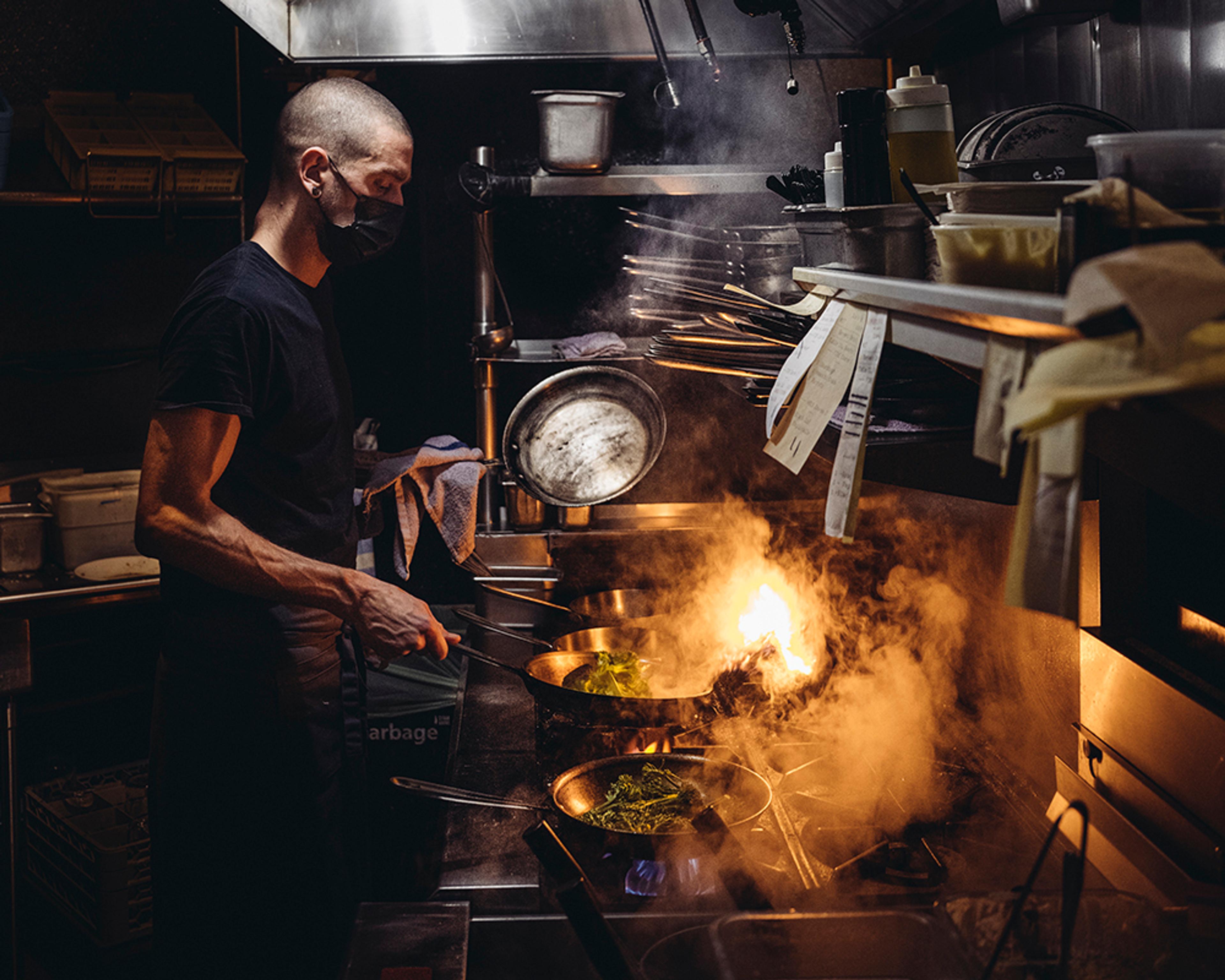 Chef cooking with flame in kitchen