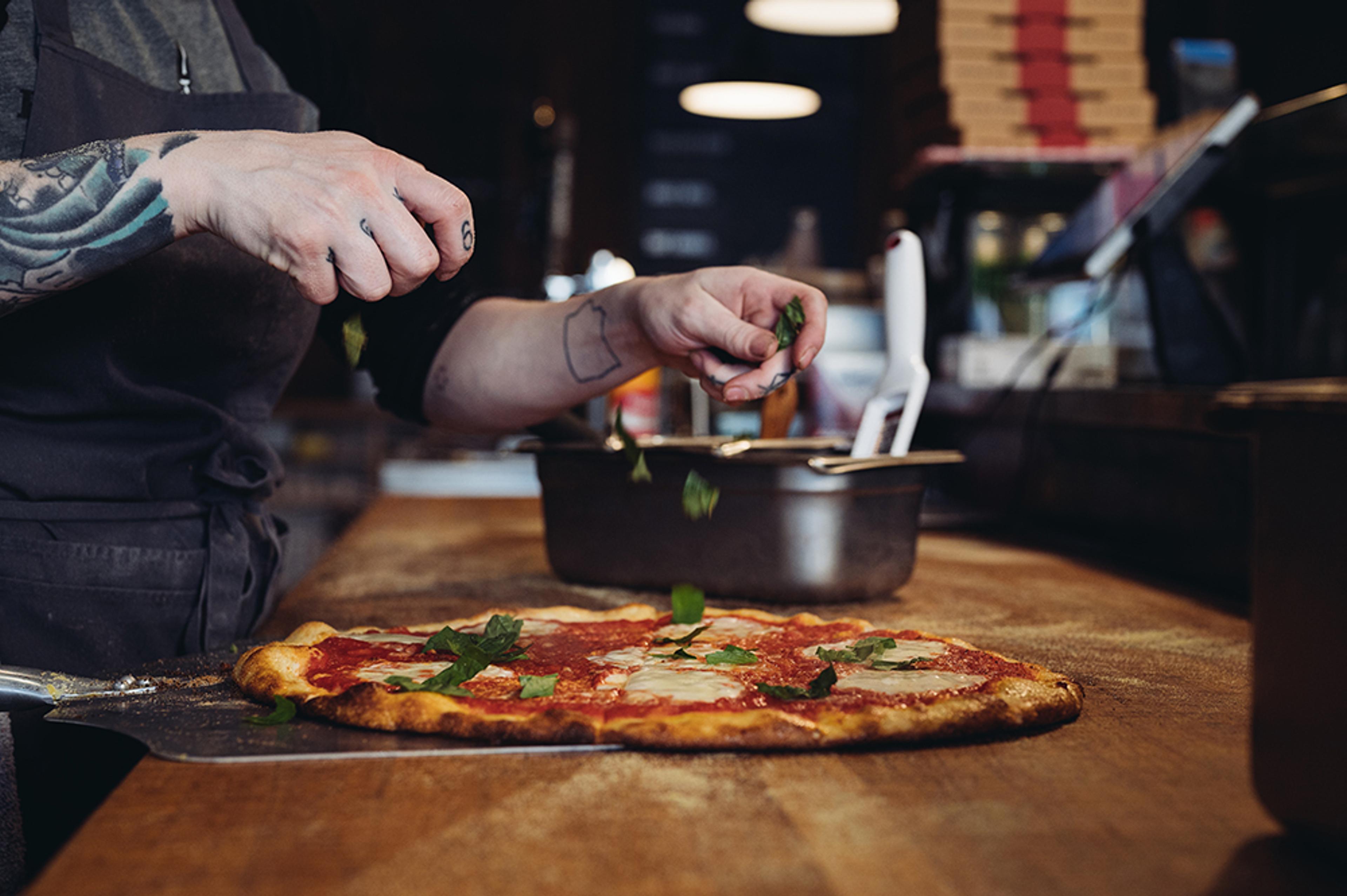 chef adding fresh basil to pizza 