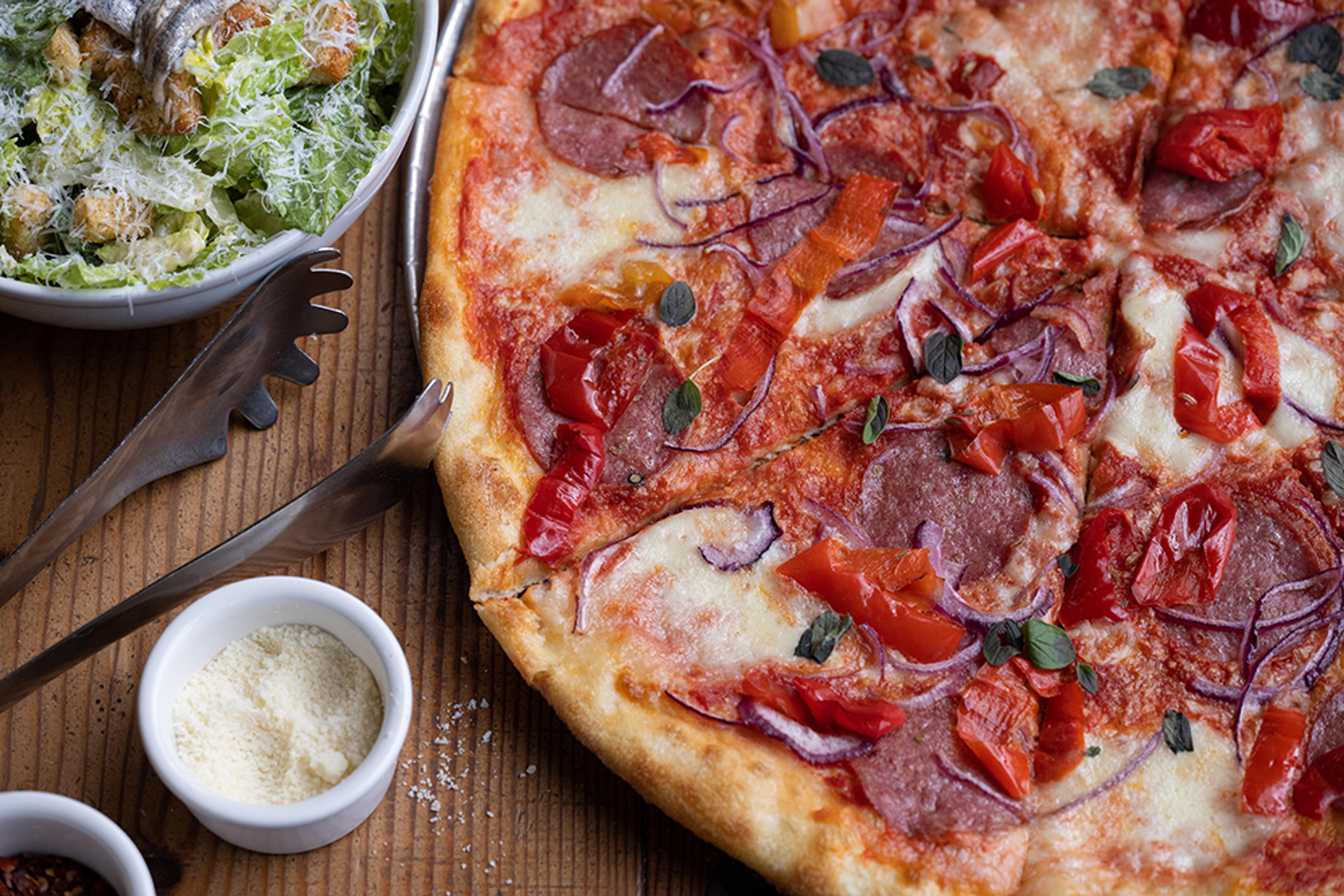 pizza topped with salami, red onions, and sweet peppers