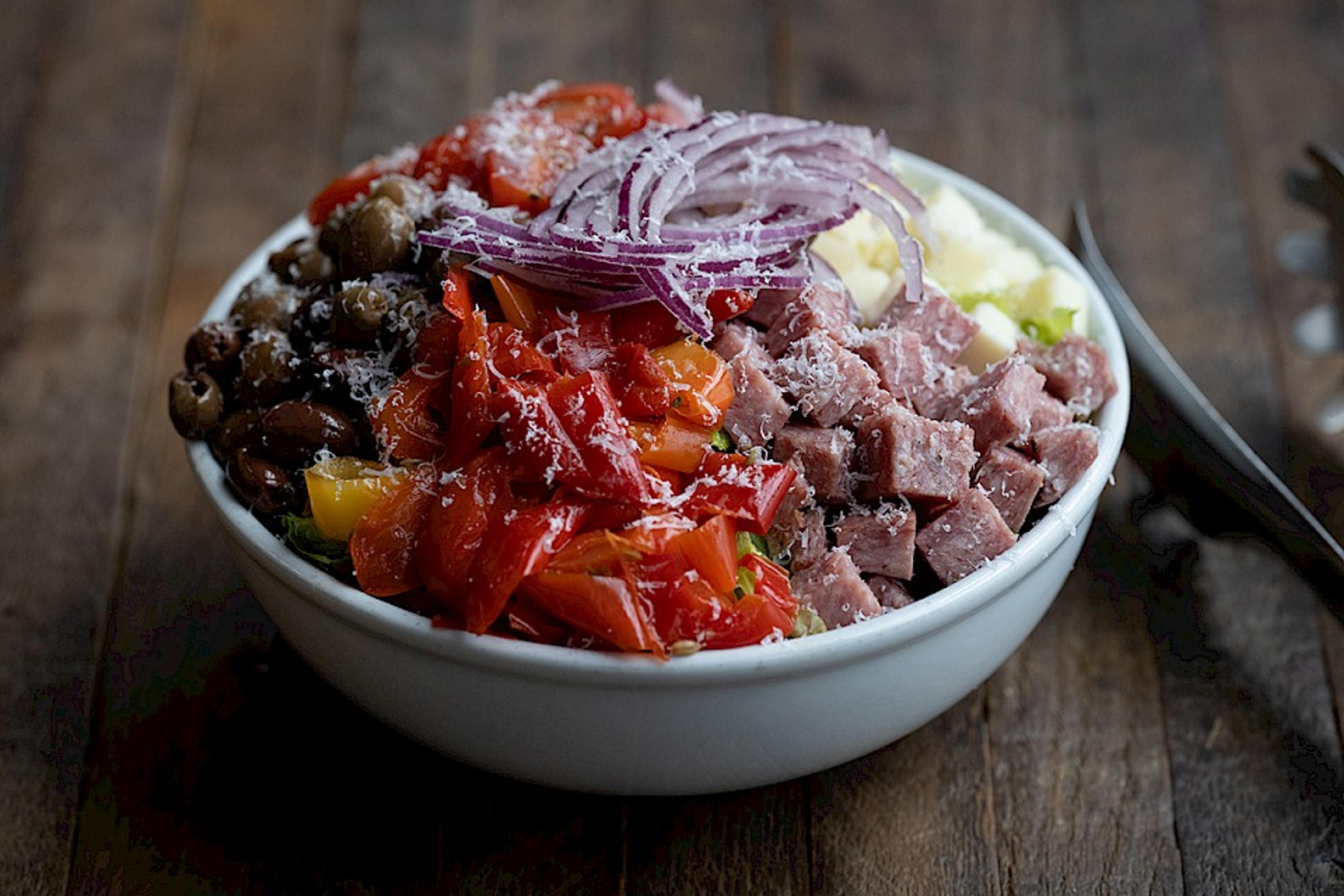 chop salad with sweet peppers, olives, red onions, tomato, ham and mozzarella