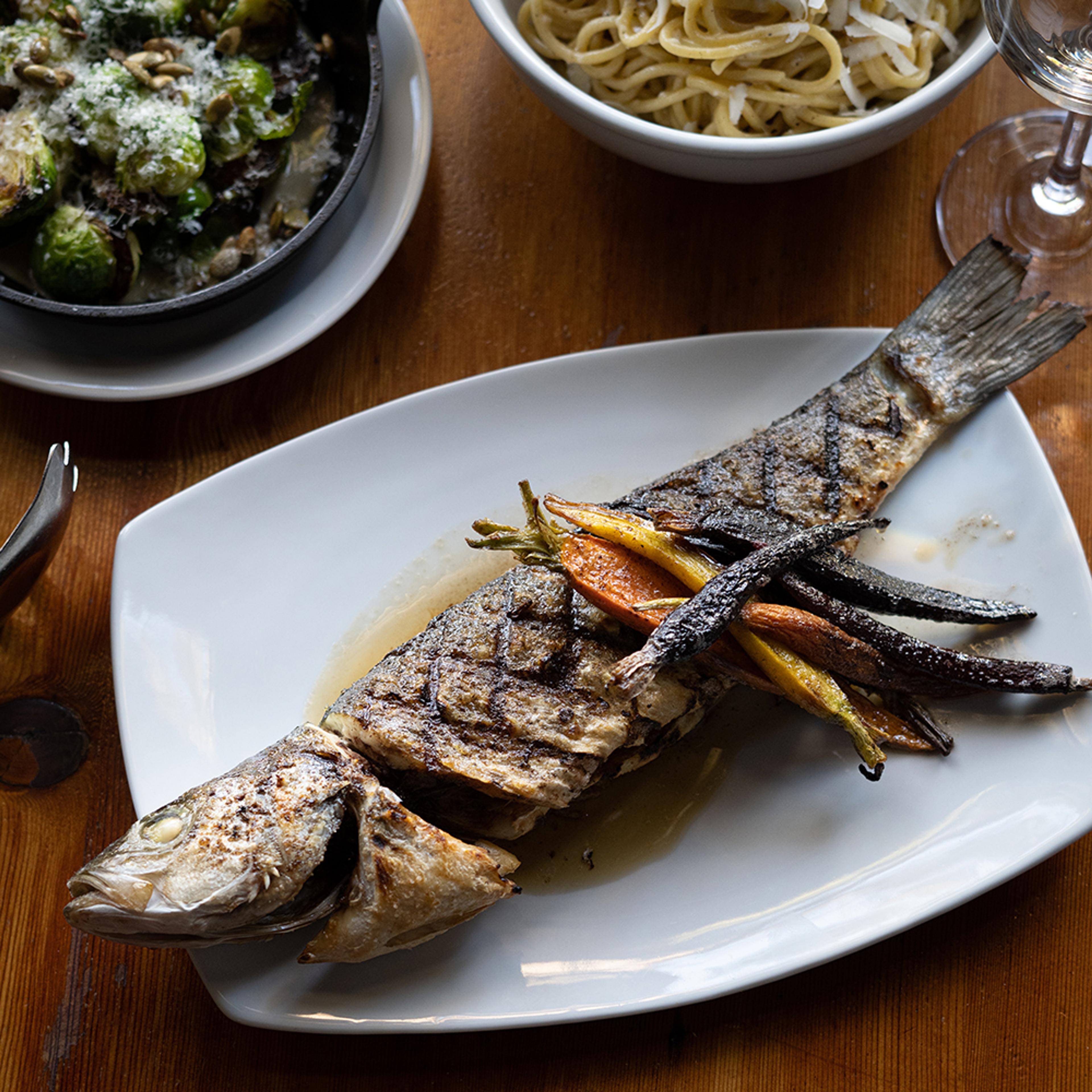 Grilled whole Branzino fish topped with roasted rainbow carrots