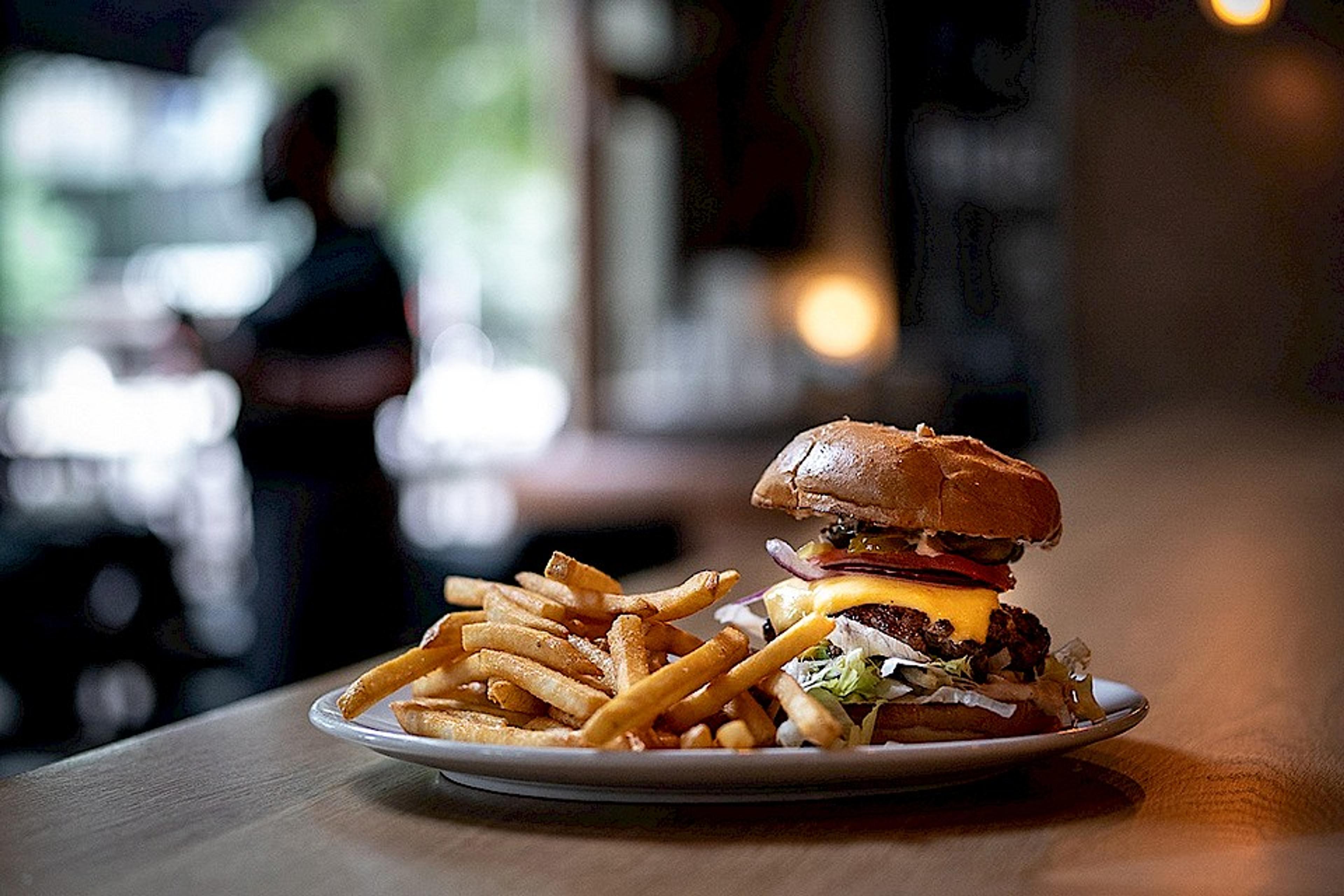 stacked burger on the bar top accompanied by fries