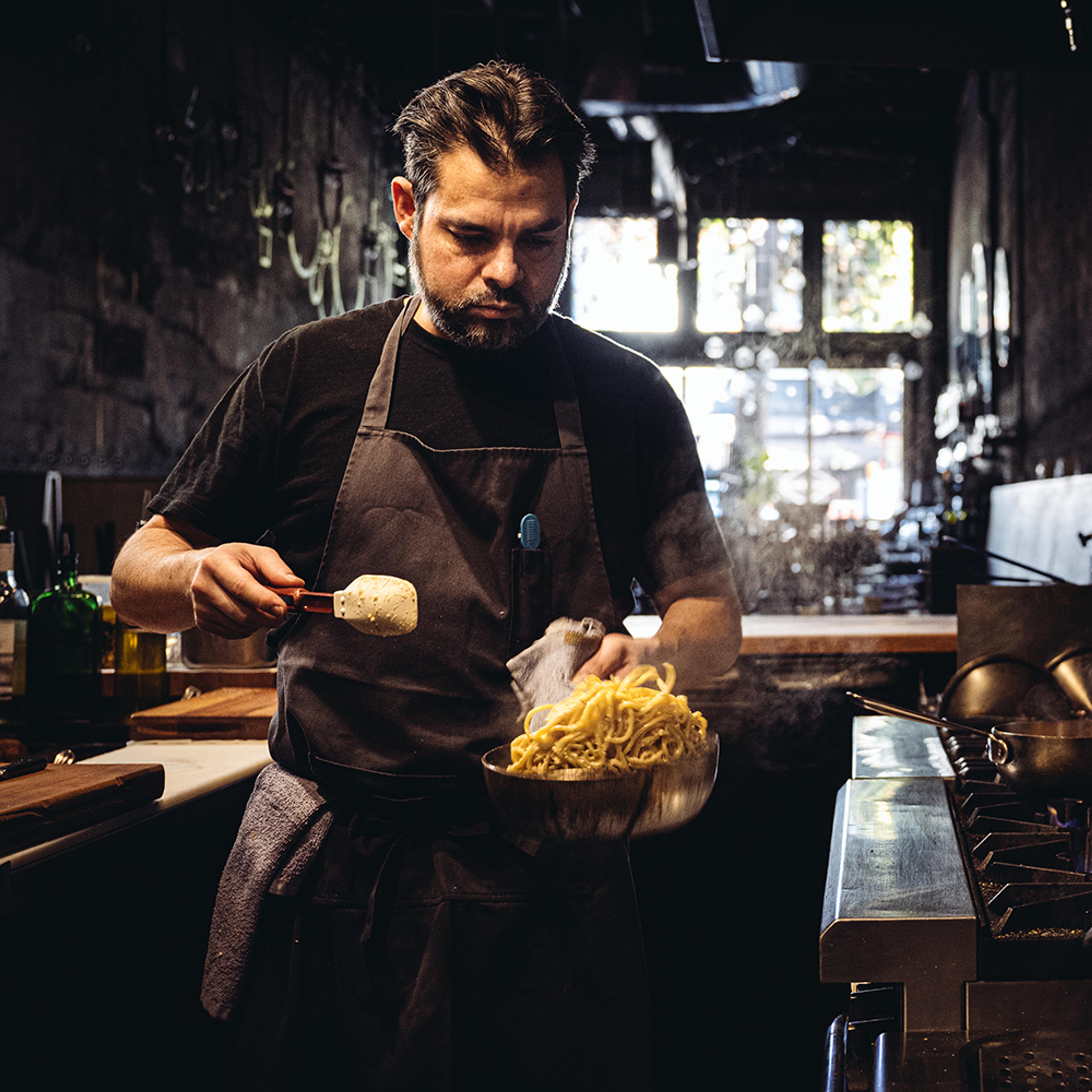 Chef tossing long noodle pasta in pot