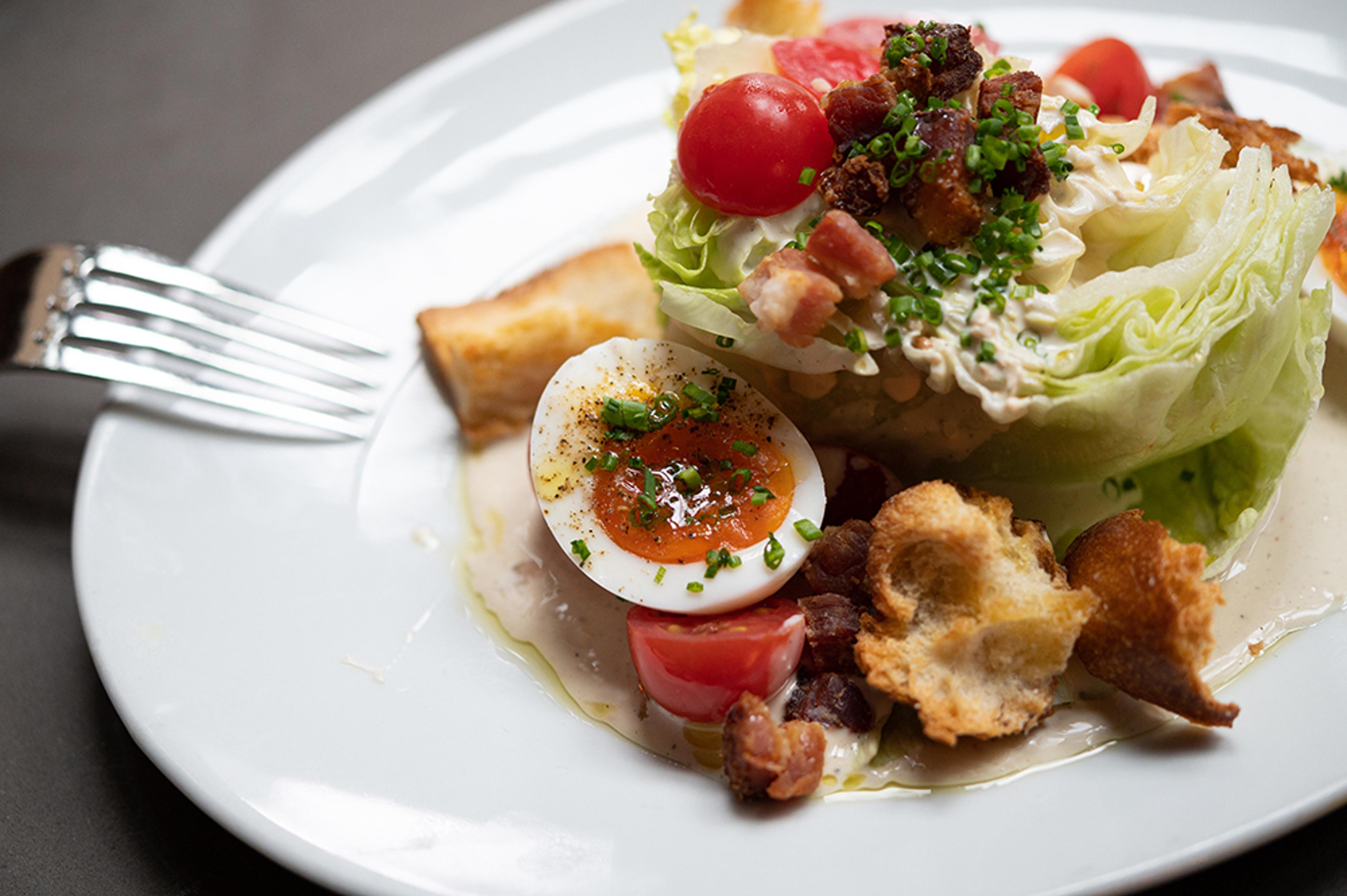 Wedge salad with soft boiled eggs, hand torn croutons, tomatoes and bacon