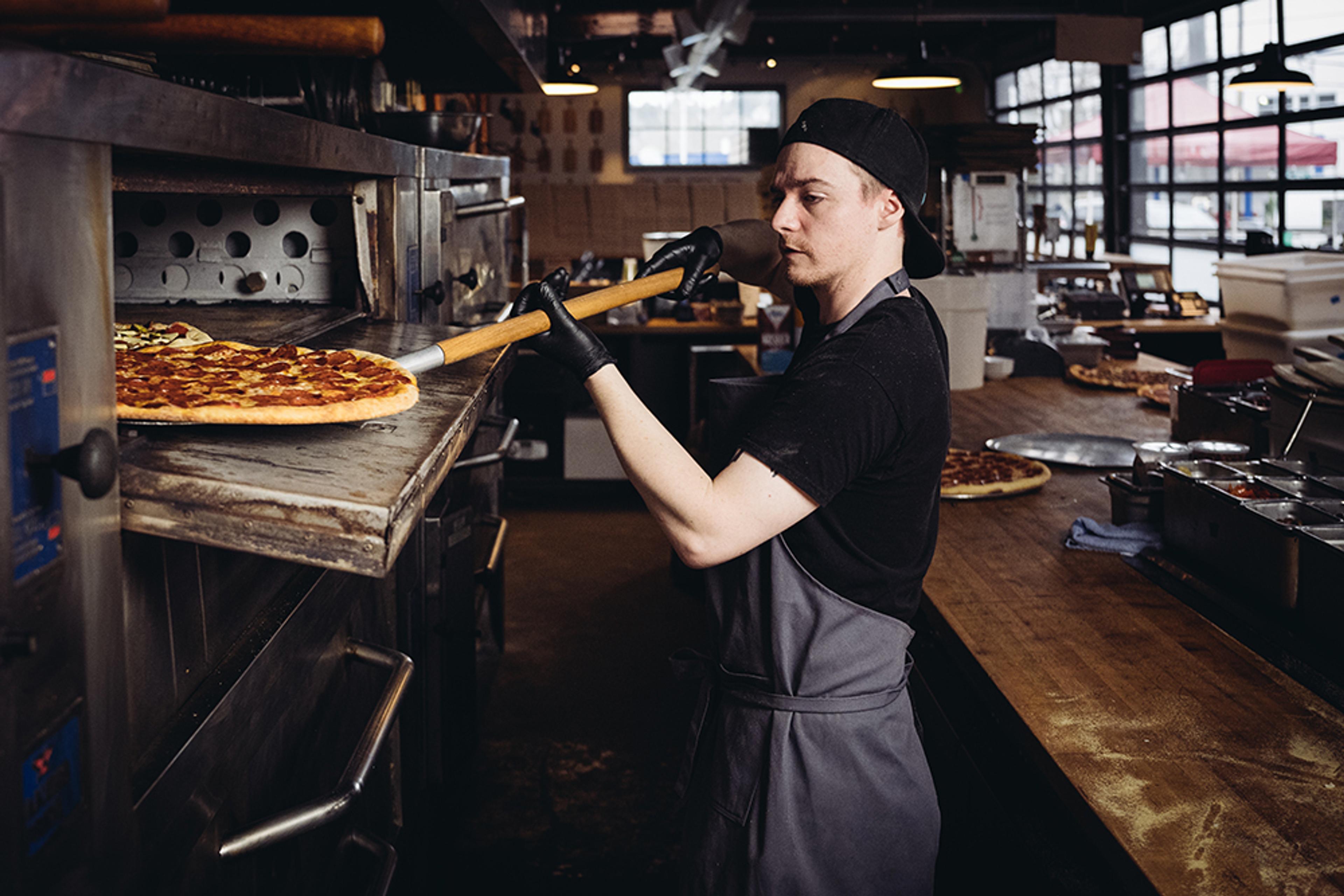 Chef placing pizza into deck oven