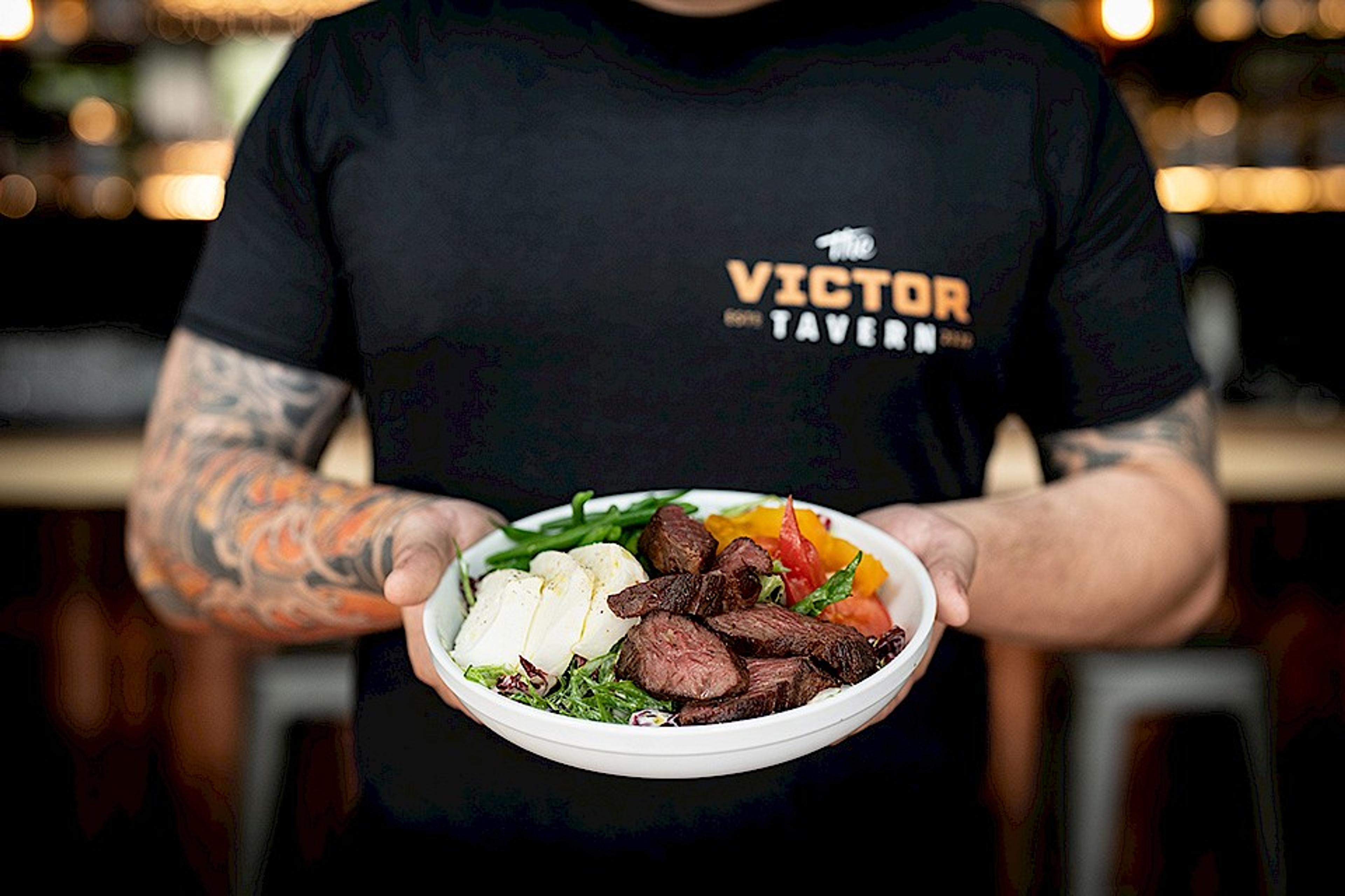 chef holding steak salad with grilled hanger steak and mozzarella