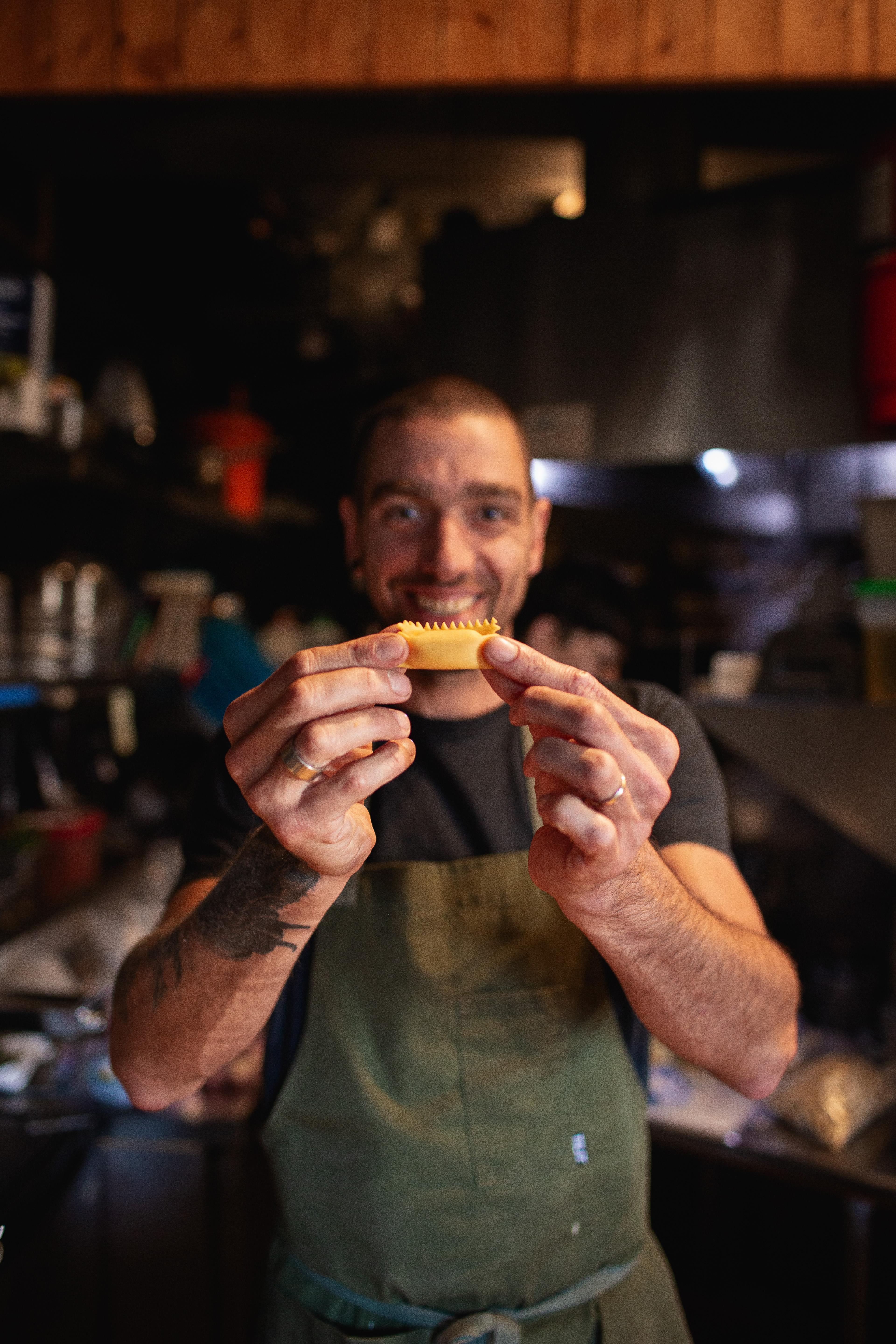 Chef smiling holding a piece of hand-stuffed pasta