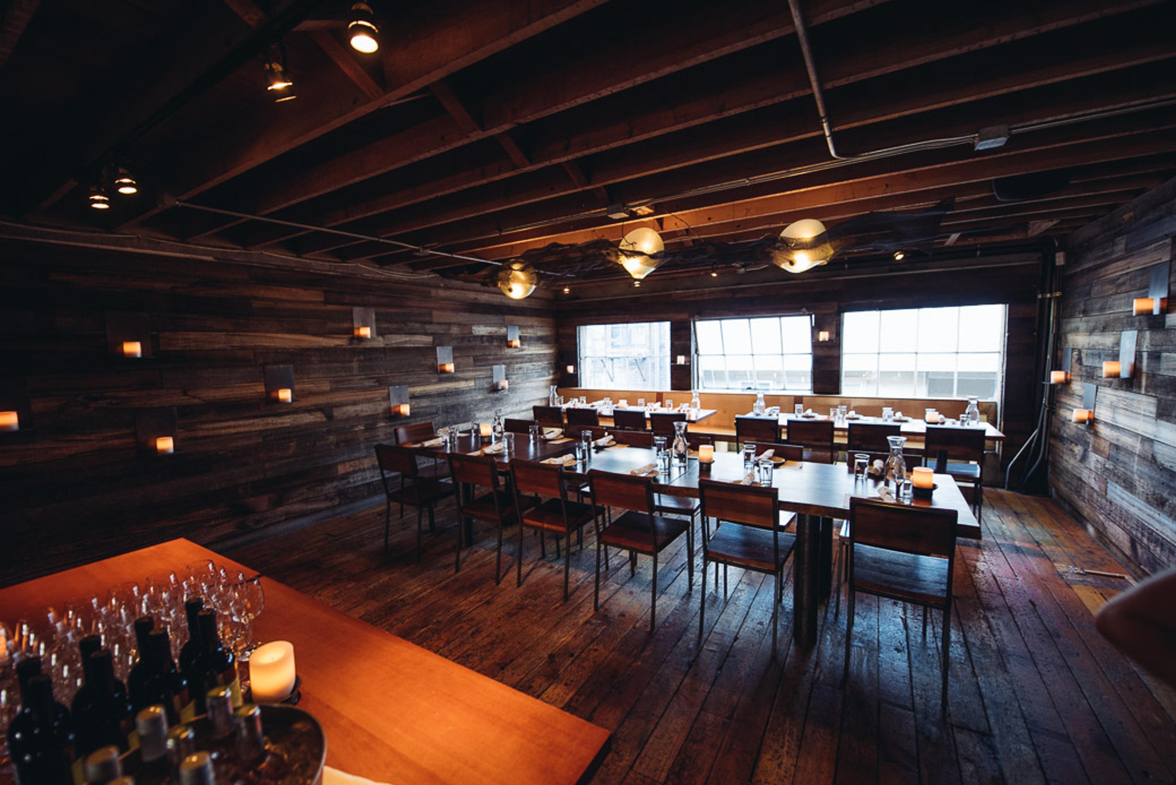 Private mezzanine dining area with reclaimed wood walls and intimate lighting