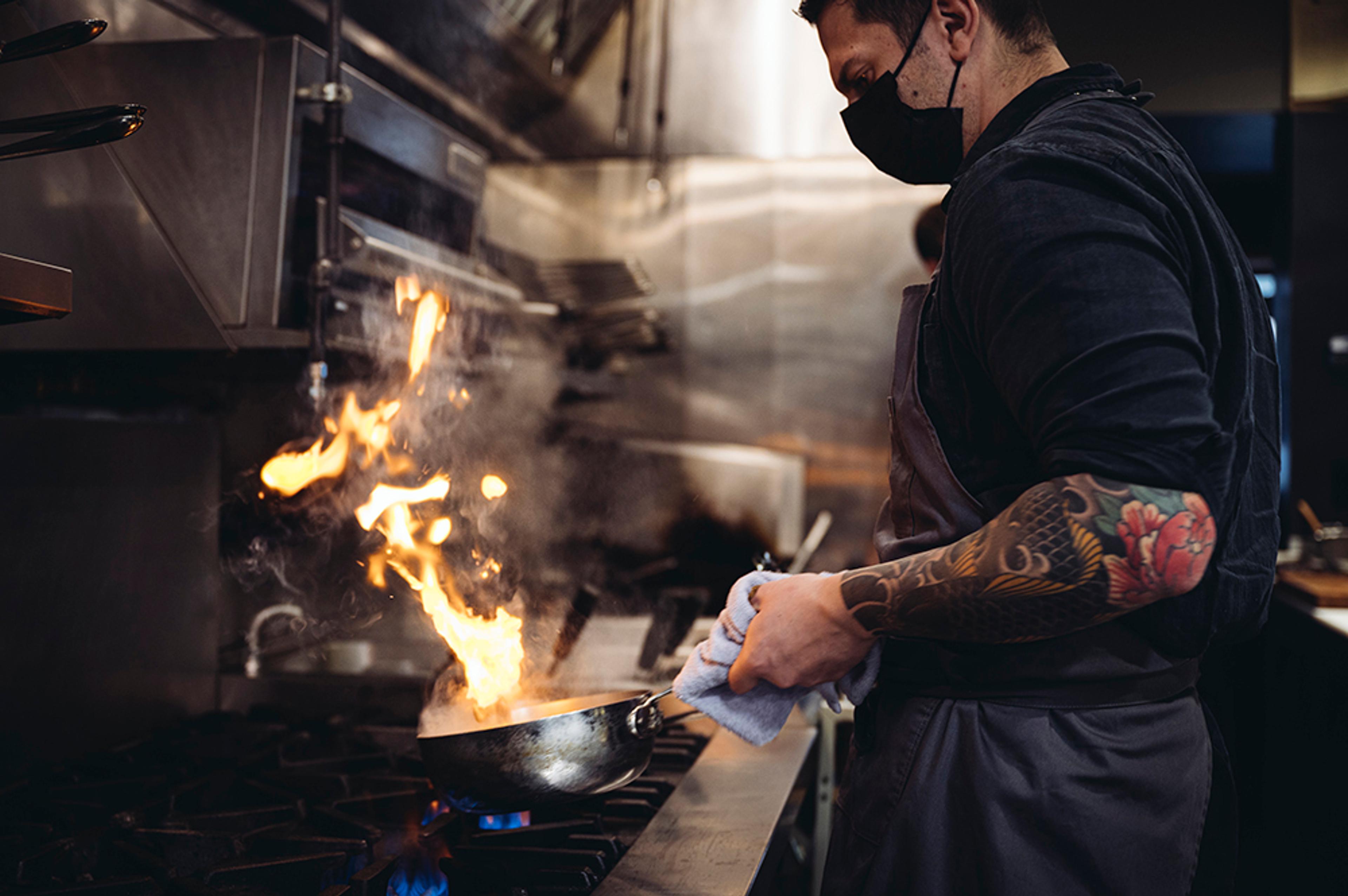 Chef cooking with flame in kitchen