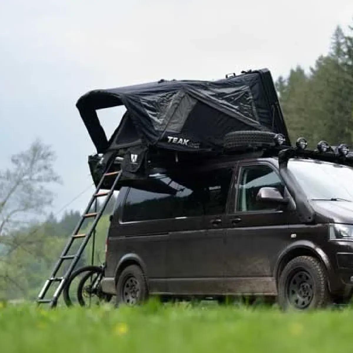 Hybrid rooftop tent pitched on a van in a grassy field