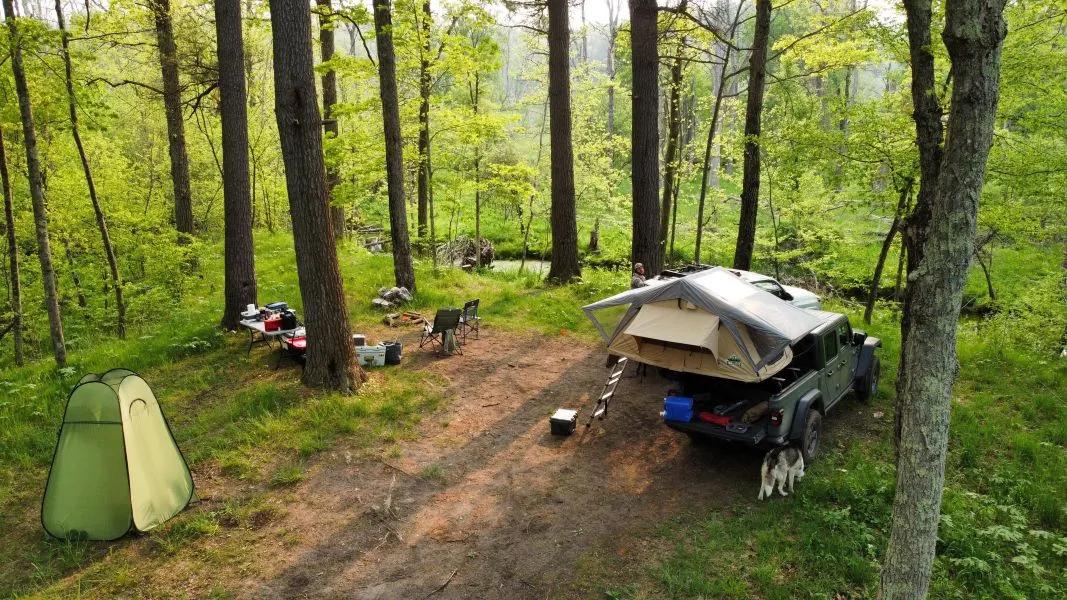 Un pick-up con una tenda da tetto aperta in un campeggio nel bosco