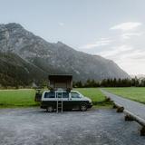 Camper van con tenda da tetto parcheggiato vicino alle montagne