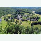Aerial view of a small village surrounded by the forested hills of the Ardennes