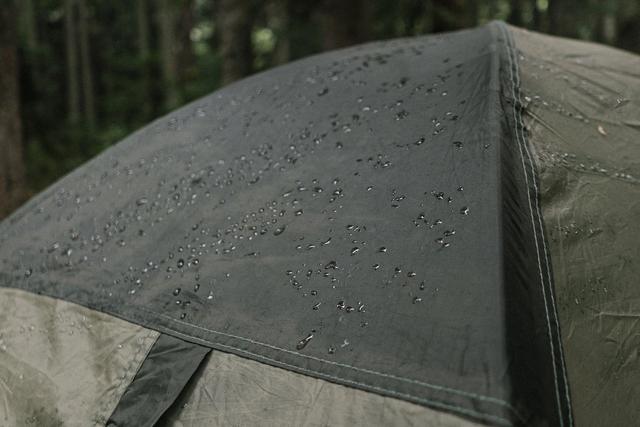 Regendruppels op nat tentdoek in een bos
