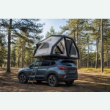 Inflatable rooftop tent mounted on an SUV at a forest campsite