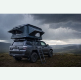 Rooftop tent secured on an SUV as rain clouds approach