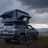 Tenda da tetto fissata su un SUV mentre si avvicinano nuvole di pioggia