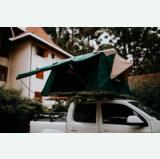 Green rooftop tent set up on a white pickup truck