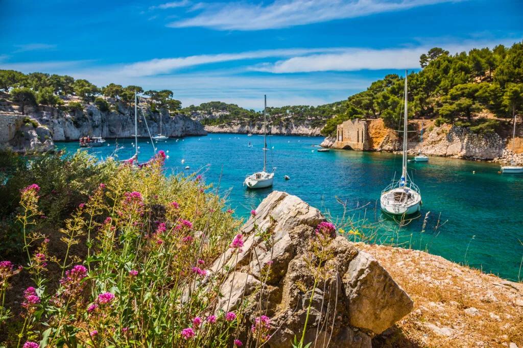 Barche a vela ancorate in una cala rocciosa dalle acque turchesi nel sud della Francia
