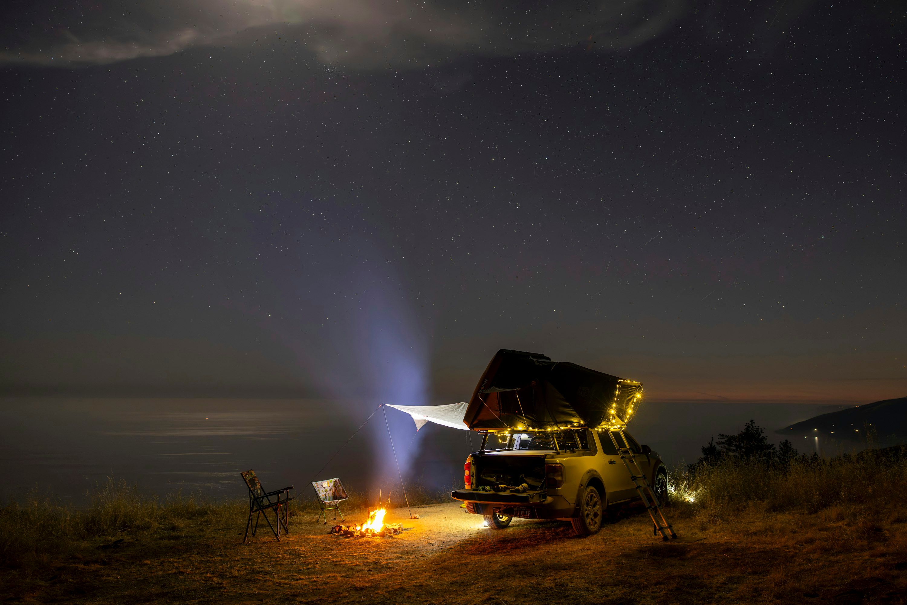 Campeggio con tenda da tetto sotto un cielo notturno stellato